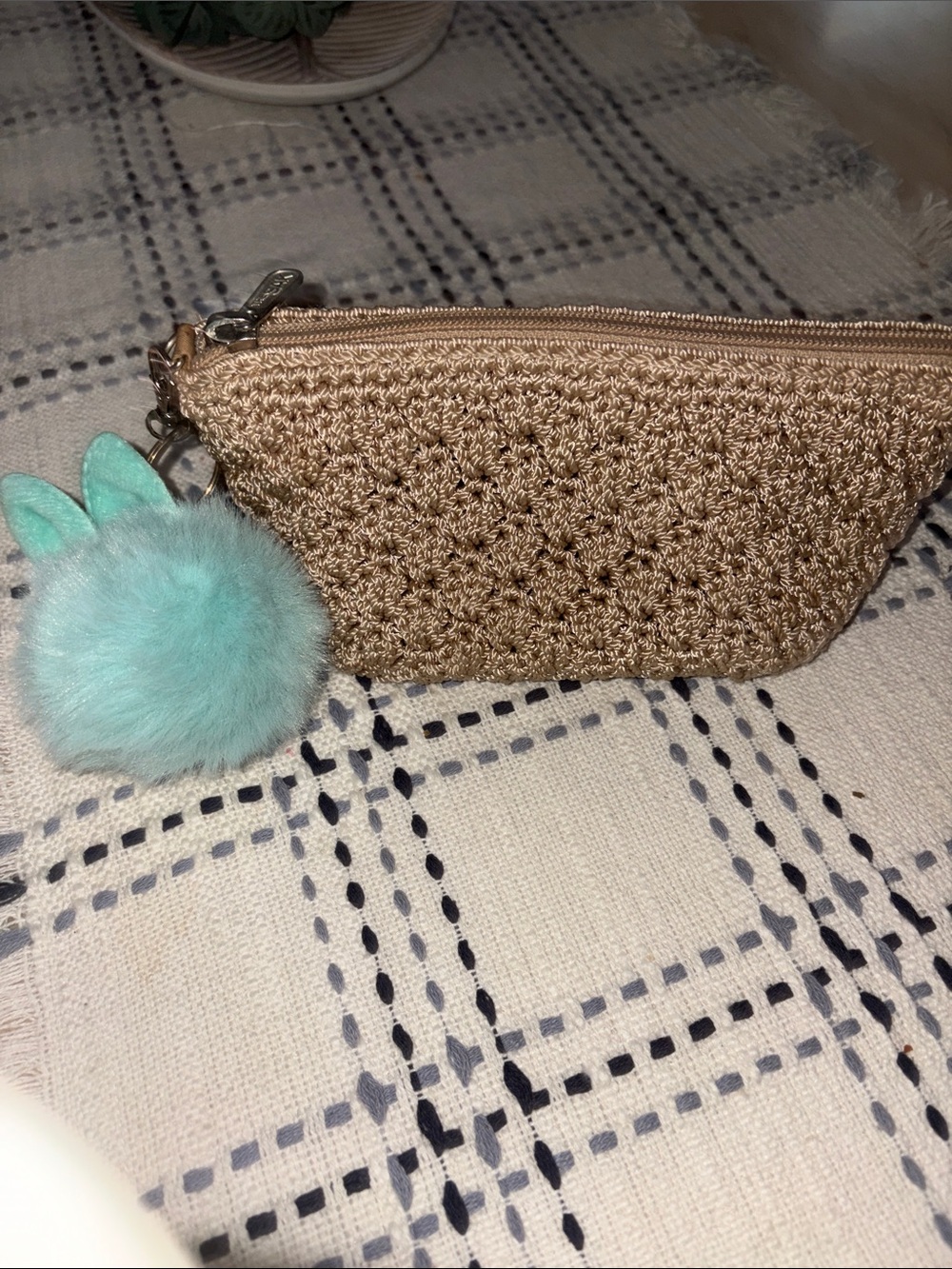 The Sak woven gold cosmetic pouch with mint pom keychain